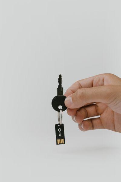 Main tenant une clé avec un porte-clés en forme de clé USB, suggérant l'utilisation d'une clé de sécurité